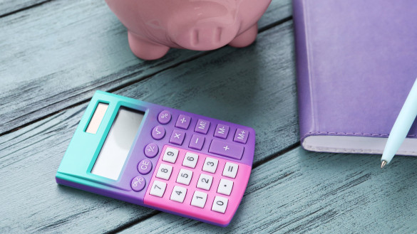 Calculator, piggy bank and notebook on blue wooden background | Featured image for debunking myths about influencer rates