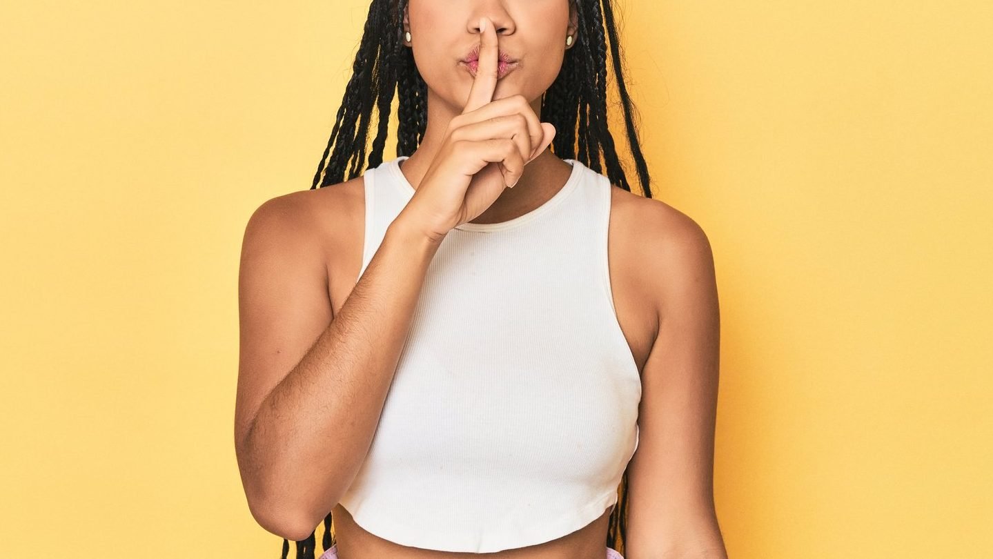 Black woman with braids holding her finger to her lips. Debunking the myth that your influencer rates have to be a secret. 